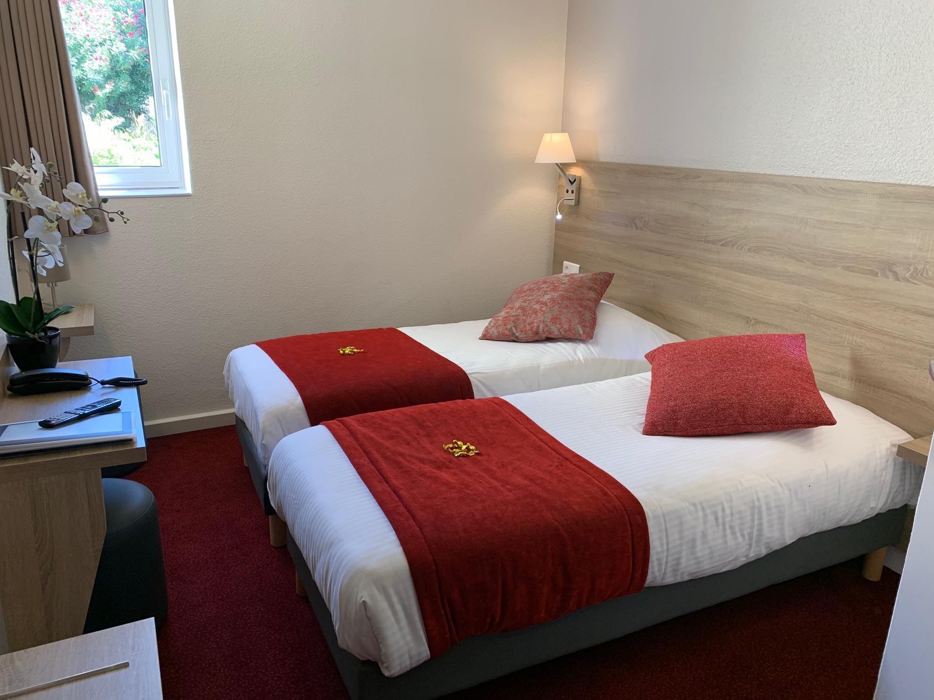 A room with cozy twin beds at hotel Costieres