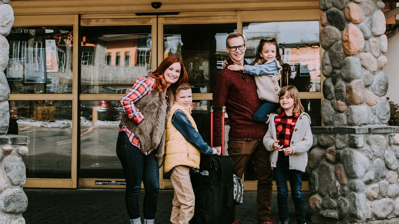family of five stands outside a hotel in Canmore