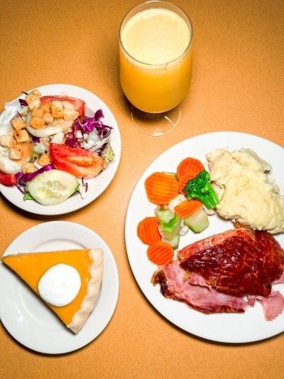 A table with three plates of Thanksgiving favorites and a refreshing drink at the Rosen Inn International Thanksgiving Day buffet.