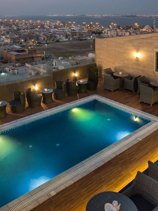 Rooftop pool featuring colorful floats by woven chairs in Sky View Café at Naviti By Warwick Dammam