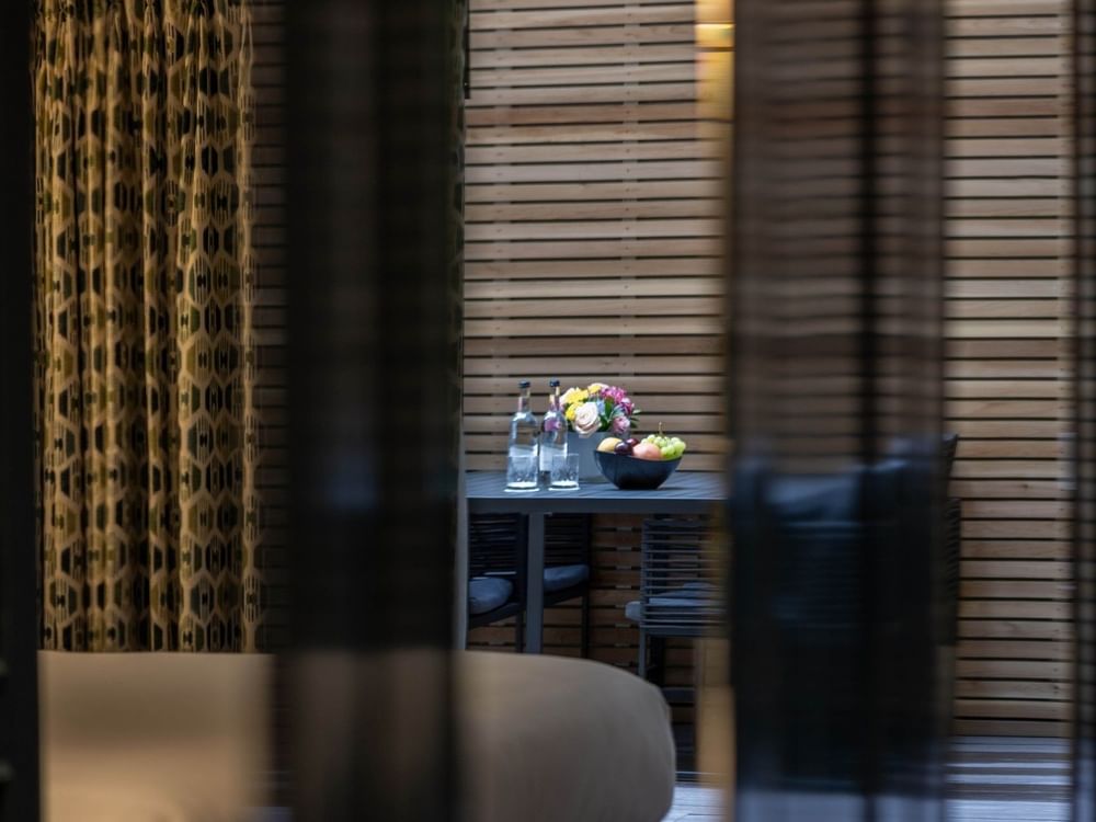 Patio table with fruit and flowers by wooden privacy screens in Hyde Park Suite at The Capital Hotel, Apartments & Townhouse