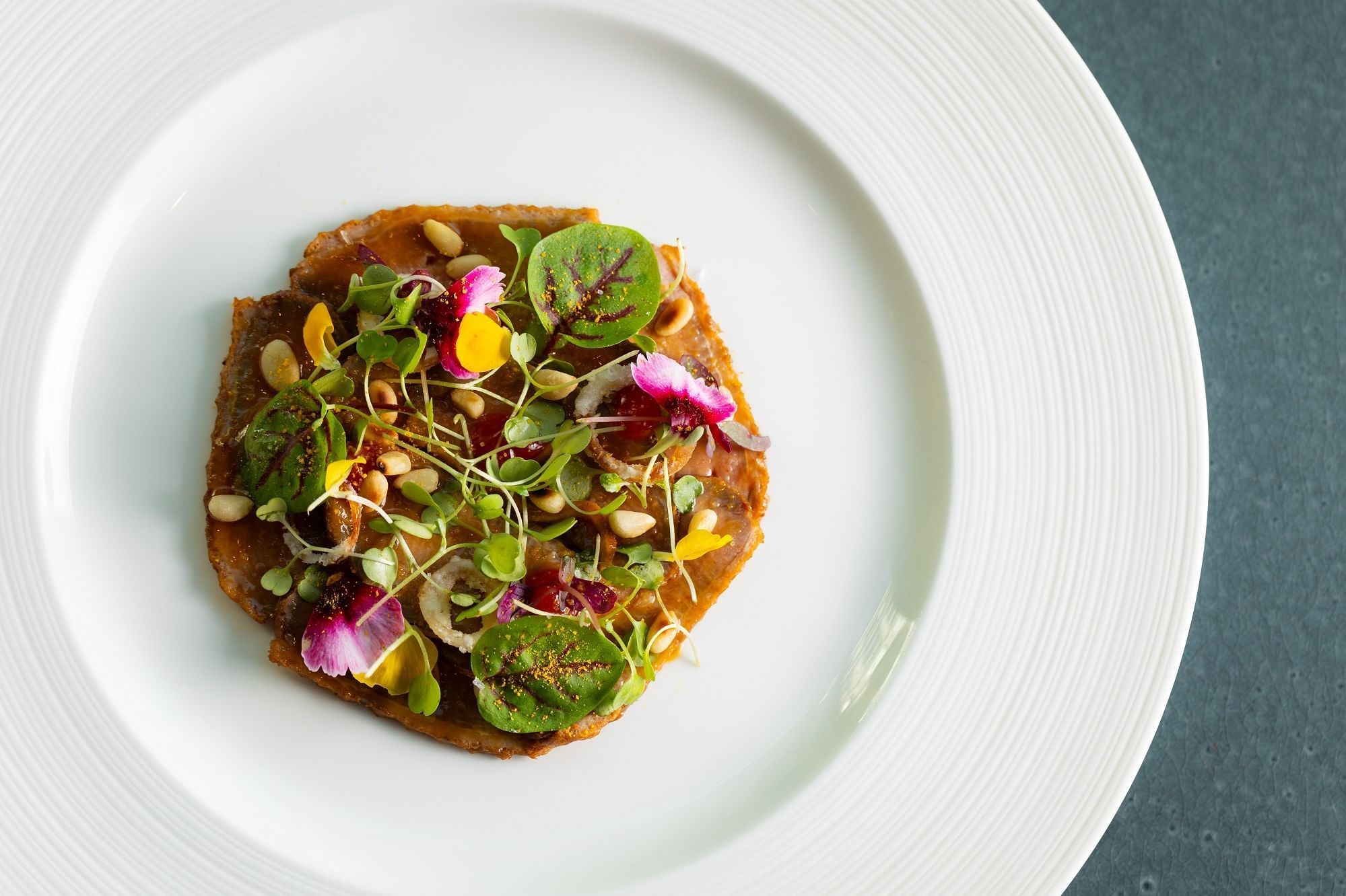 Close-up of a Spicy smoked duck with orange dressing and pine nuts served at The Londoner