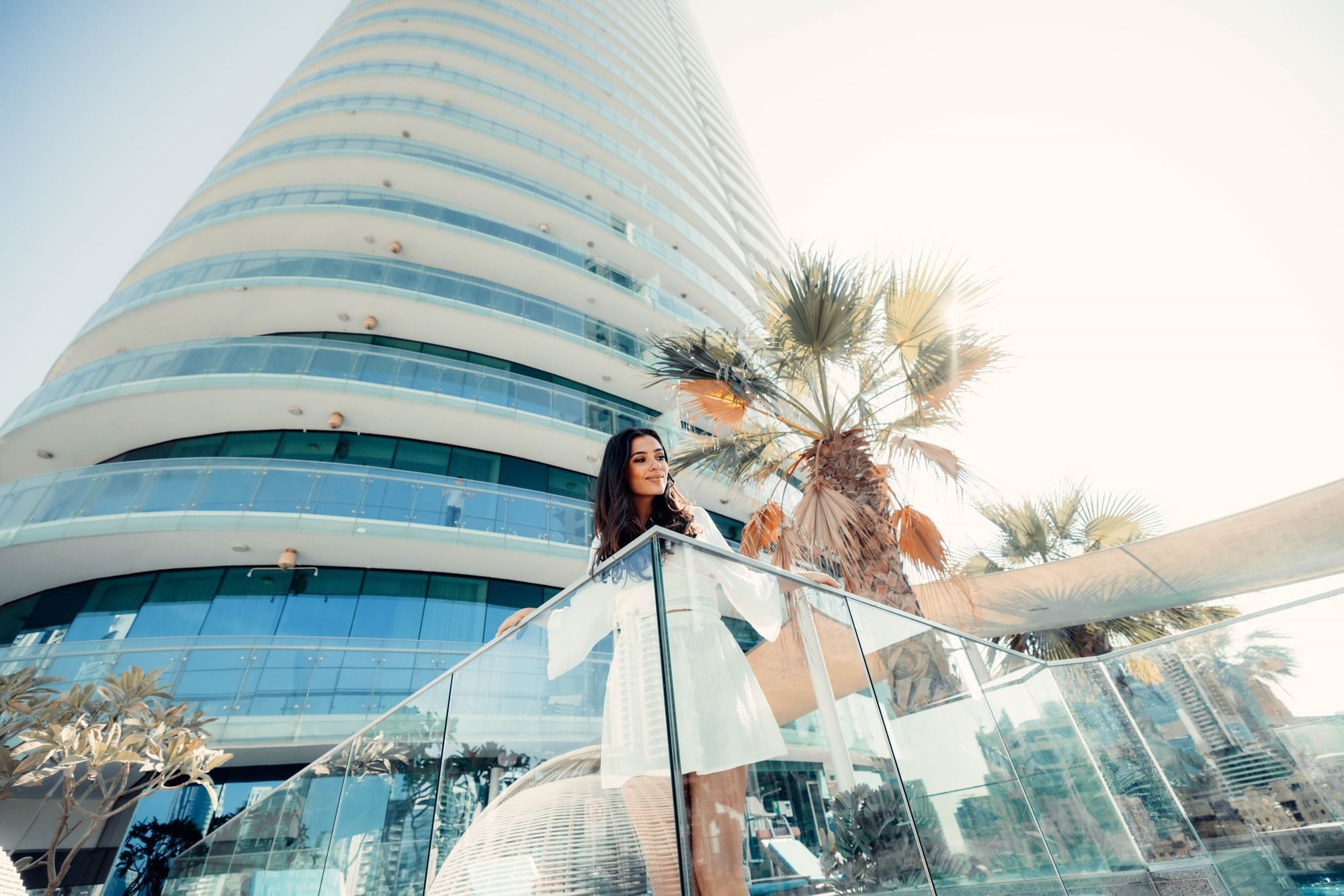 A woman looking down from a balcony at DAMAC Maison Distinction
