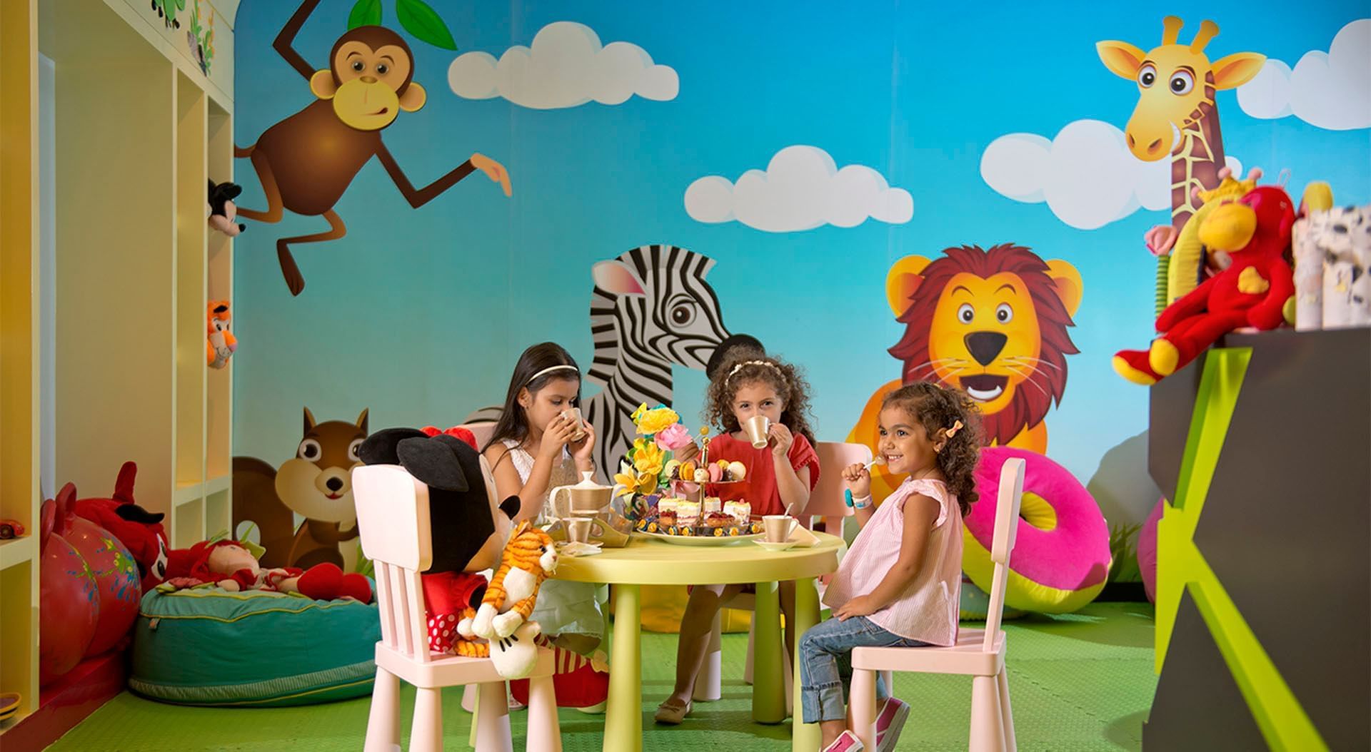 Children having tea in the Kids Club with a colorful animal theme and plush toys at DAMAC Maison Mall Street