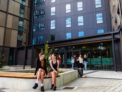 Modern courtyard with students relaxing on concrete benches surrounded by contemporary multi-story buildings at Tupuārangi