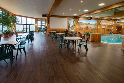 The large seating area next to the indoor pool at Lake Placid Club Grandview with round tables and a scenic nature mural