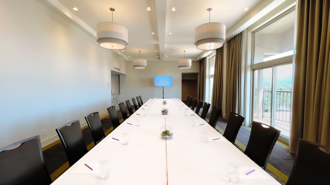 Long boardroom table set with water, pens and chairs