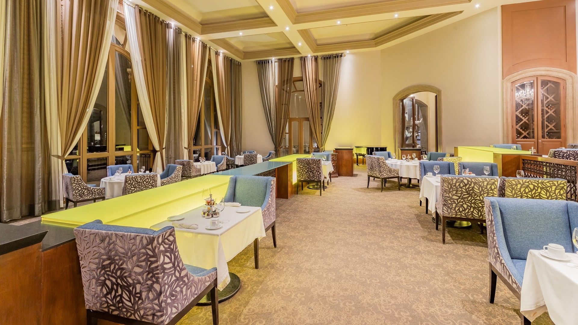Tierra Mía restaurant with blue patterned chairs and tall, elegant window drapes at Quinta Real Monterrey