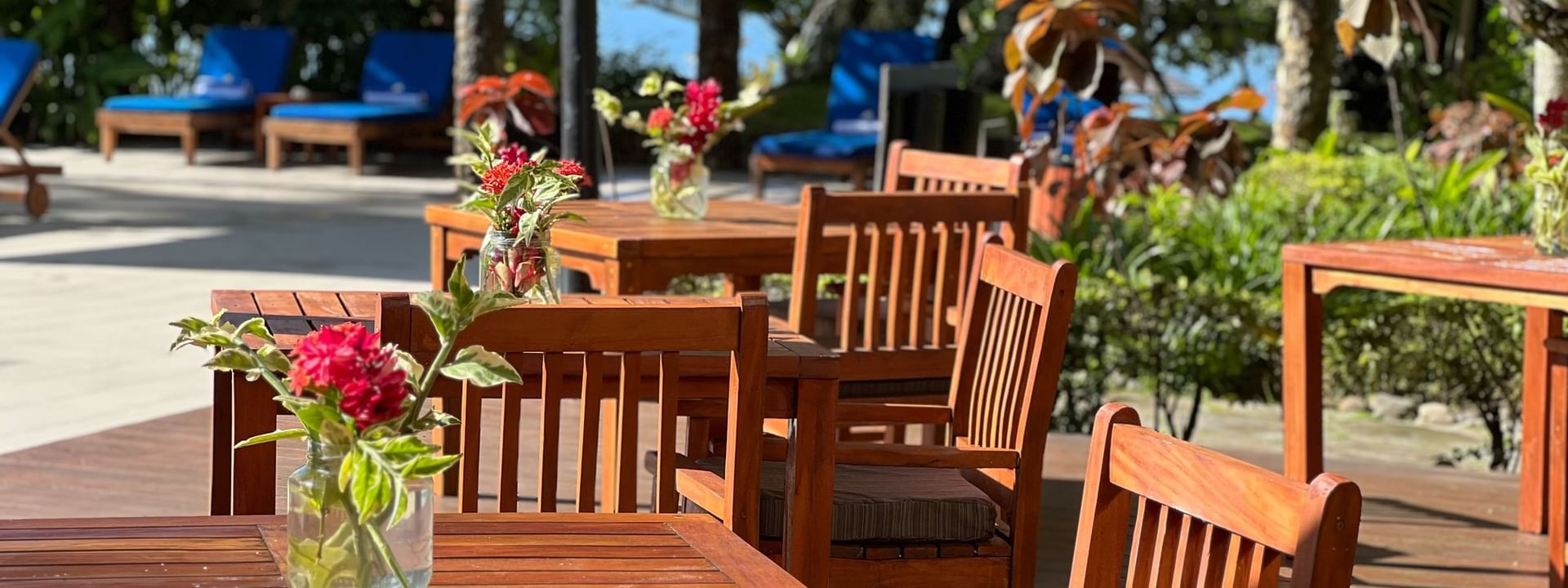 Outdoor wooden dining area with tables and chairs near the adult-only pool and bar at Warwick Fiji Resort and Spa, Korolevu