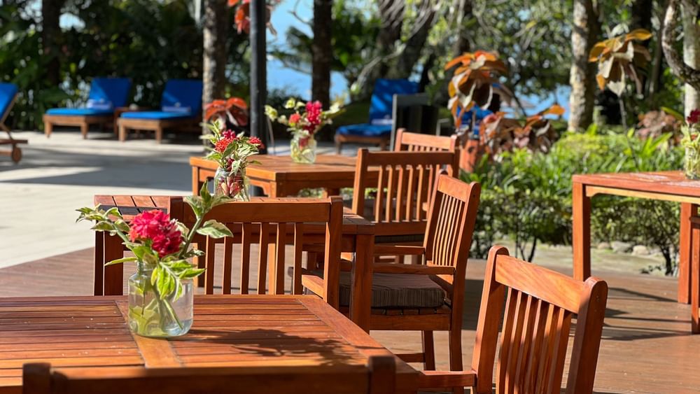 Outdoor wooden dining area with tables and chairs near the adult-only pool and bar at Warwick Fiji Resort and Spa, Korolevu.