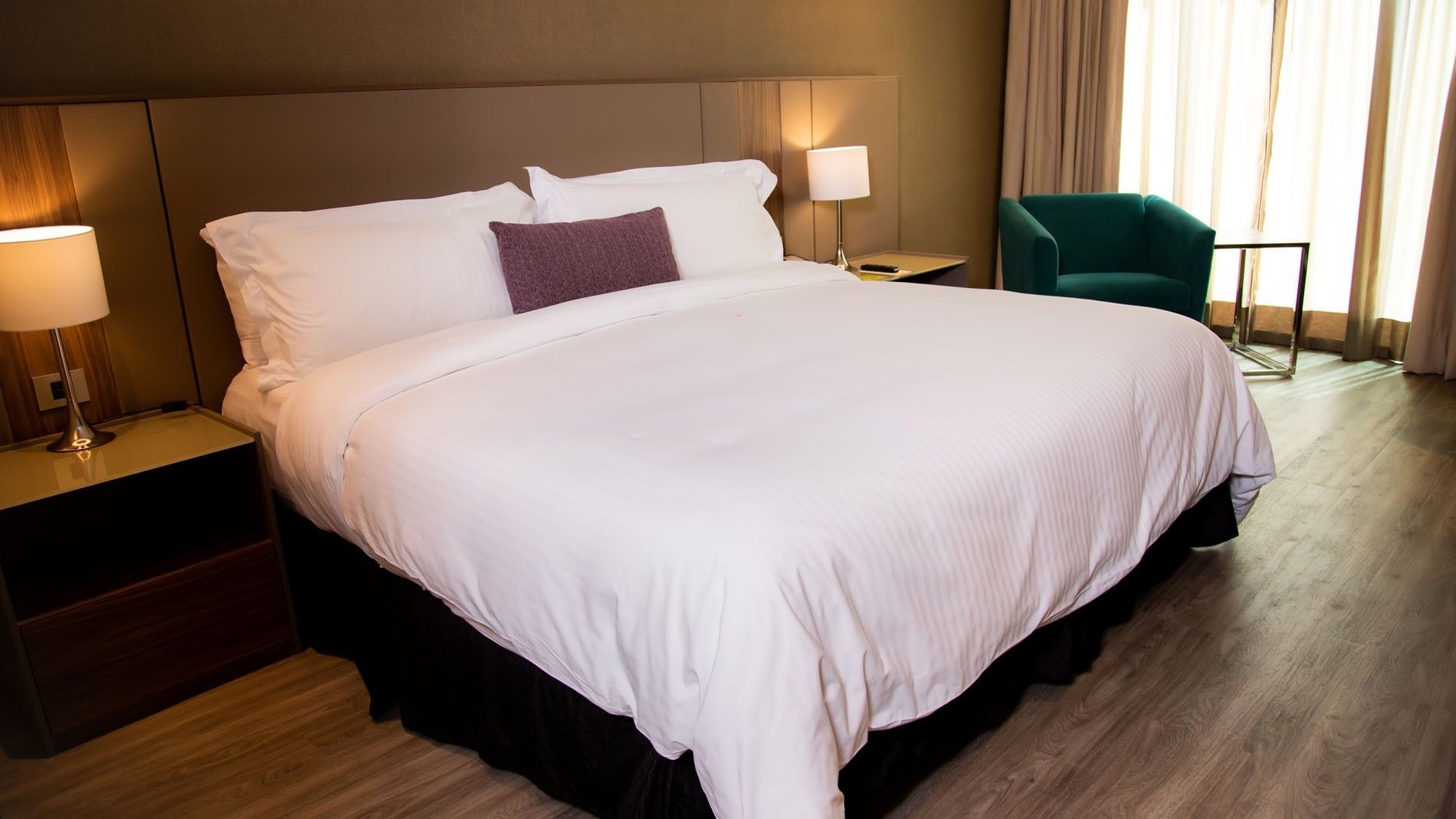 King Deluxe bed with white sheets and a purple accent pillow at Camino Real Fashion Drive, Monterrey