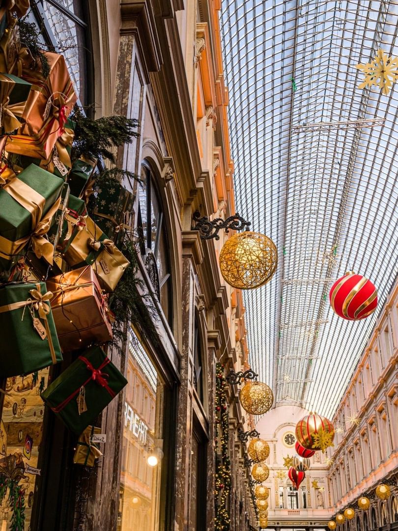 Festive shopping arcade with hanging gift boxes and ornaments under a glass ceiling at Hotel Barsey by Warwick - Brussels