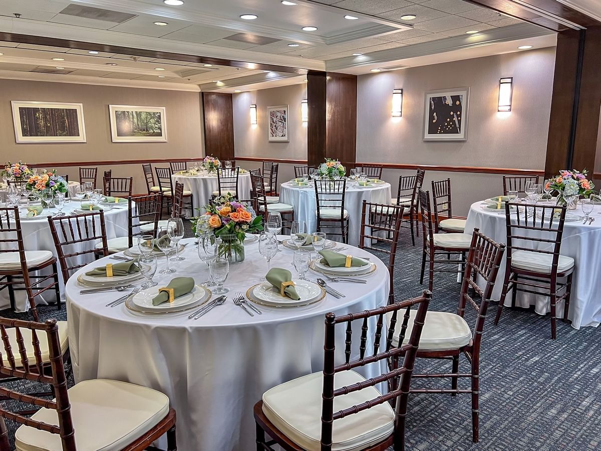 Sasquatch Room featuring round tables with white cloths by dark wooden chairs at Warwick Seattle
