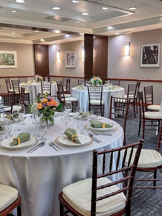 Sasquatch Room event setup with round tables, white linens, green napkins, and bright floral centerpieces at Warwick Seattle