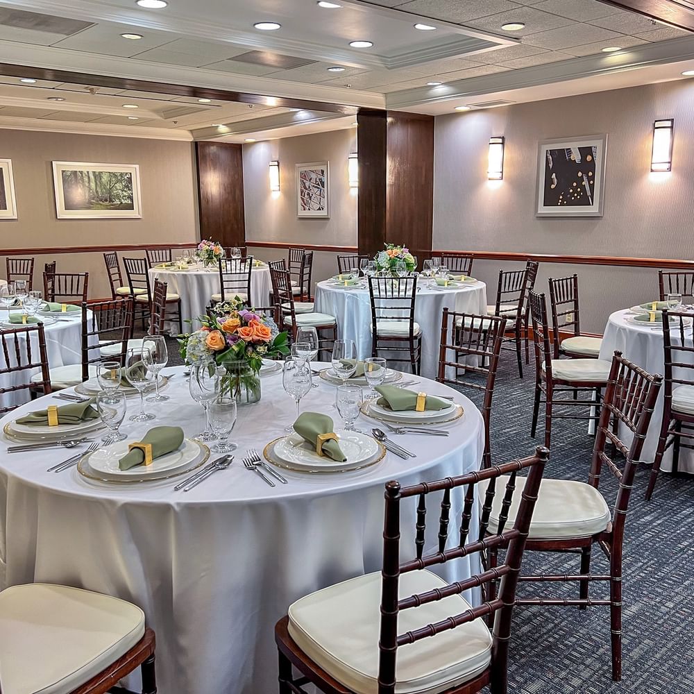 Sasquatch Room featuring round tables with white cloths by dark wooden chairs at Warwick Seattle