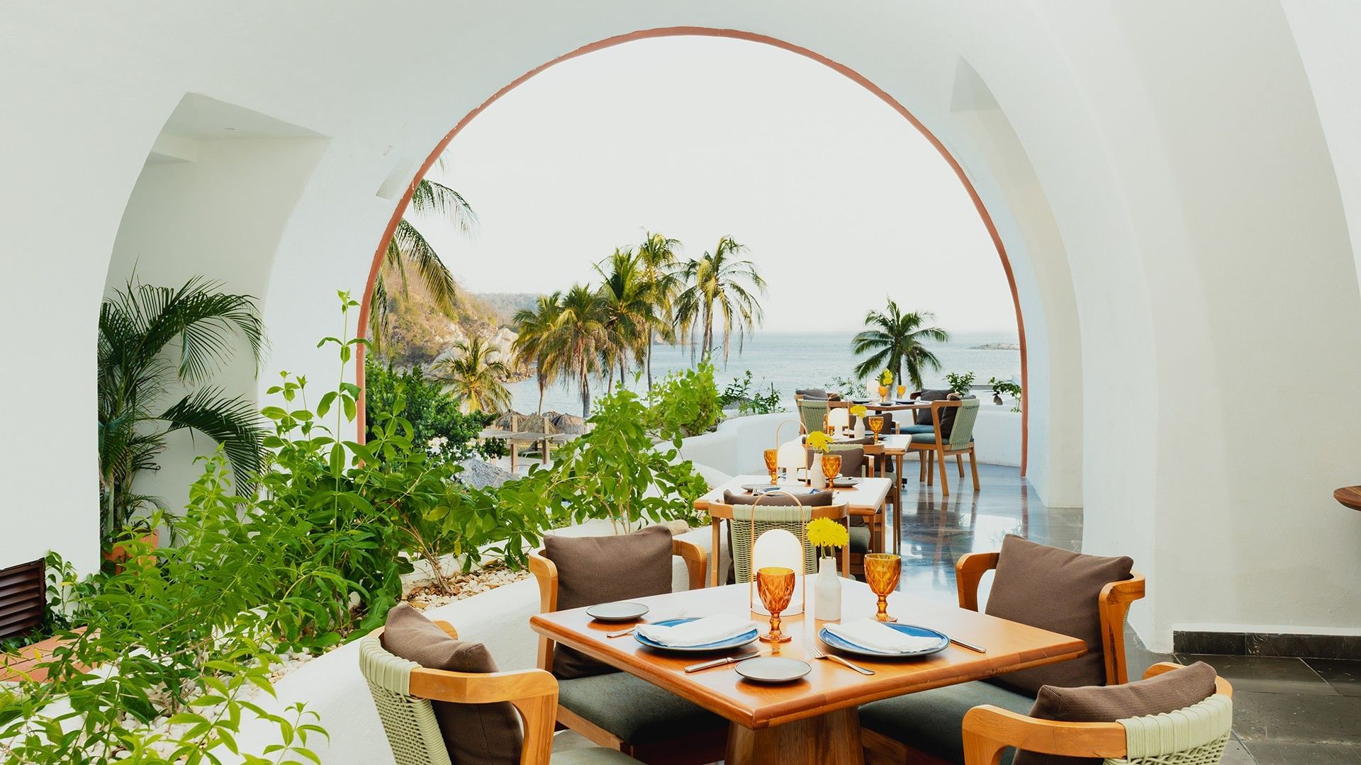 Dining area with plush seating and a large white arch, overlooking the ocean in Chez Binni at Camino Real Zaashila Huatulco