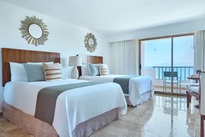A spacious luxury suite interior showing an elegant seating area next to panoramic ocean-view windows.