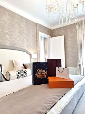 Luxury room featuring a chandelier, elegant wallpaper, and fashion bags on the bed at Hôtel Westminster - Paris