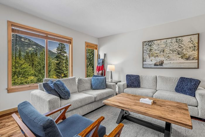 Bright living room with mountain view, couches and wooden table at Spring Creek Vacation Homes Canmore