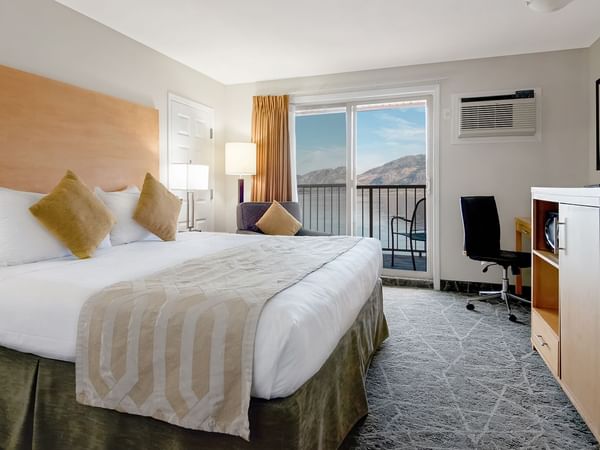 Hotel room with a king-size bed, desk, and lake view from the balcony.