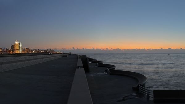 Beirut Waterfront Promenade with stone benches by the sea under an orange sky near Warwick Palm Beach Hotel