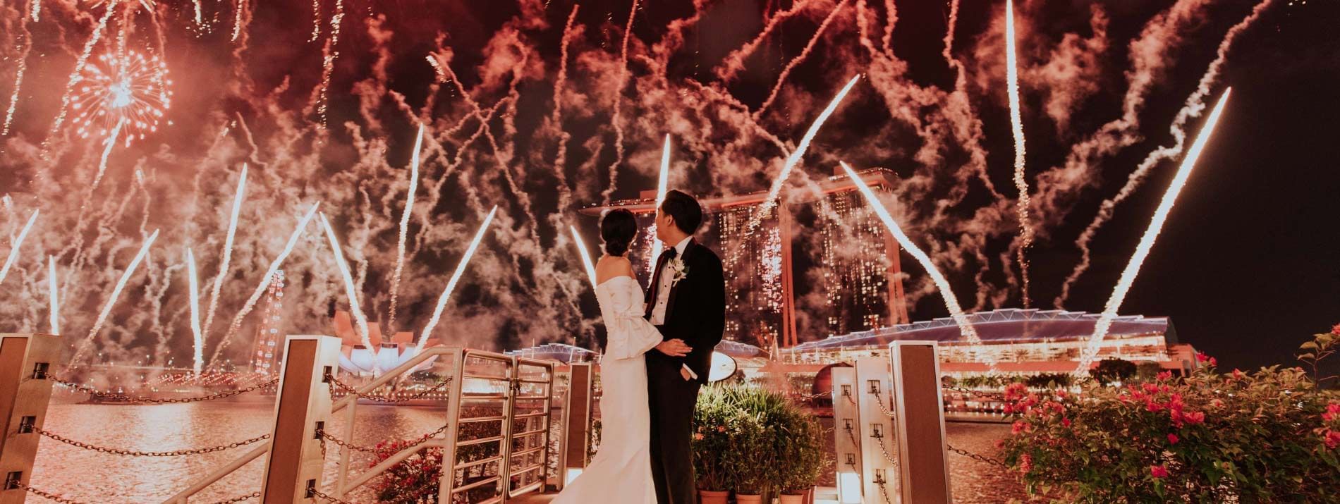 Wedded couple watching fireworks in the background of them at The Fullerton Hotels and Resorts