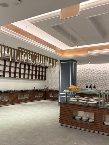 Buffet counters by a textured wall under gold decorative slats in Almir Restaurant at Warwick Jeddh Hotel & Spa