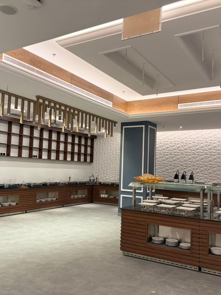 Buffet counters by a textured wall under gold decorative slats in Almir Restaurant at Warwick Jeddh Hotel & Spa