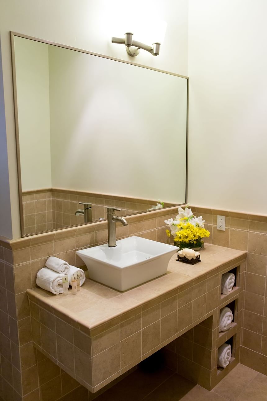 bathroom with raised sink and big mirror with folded towels