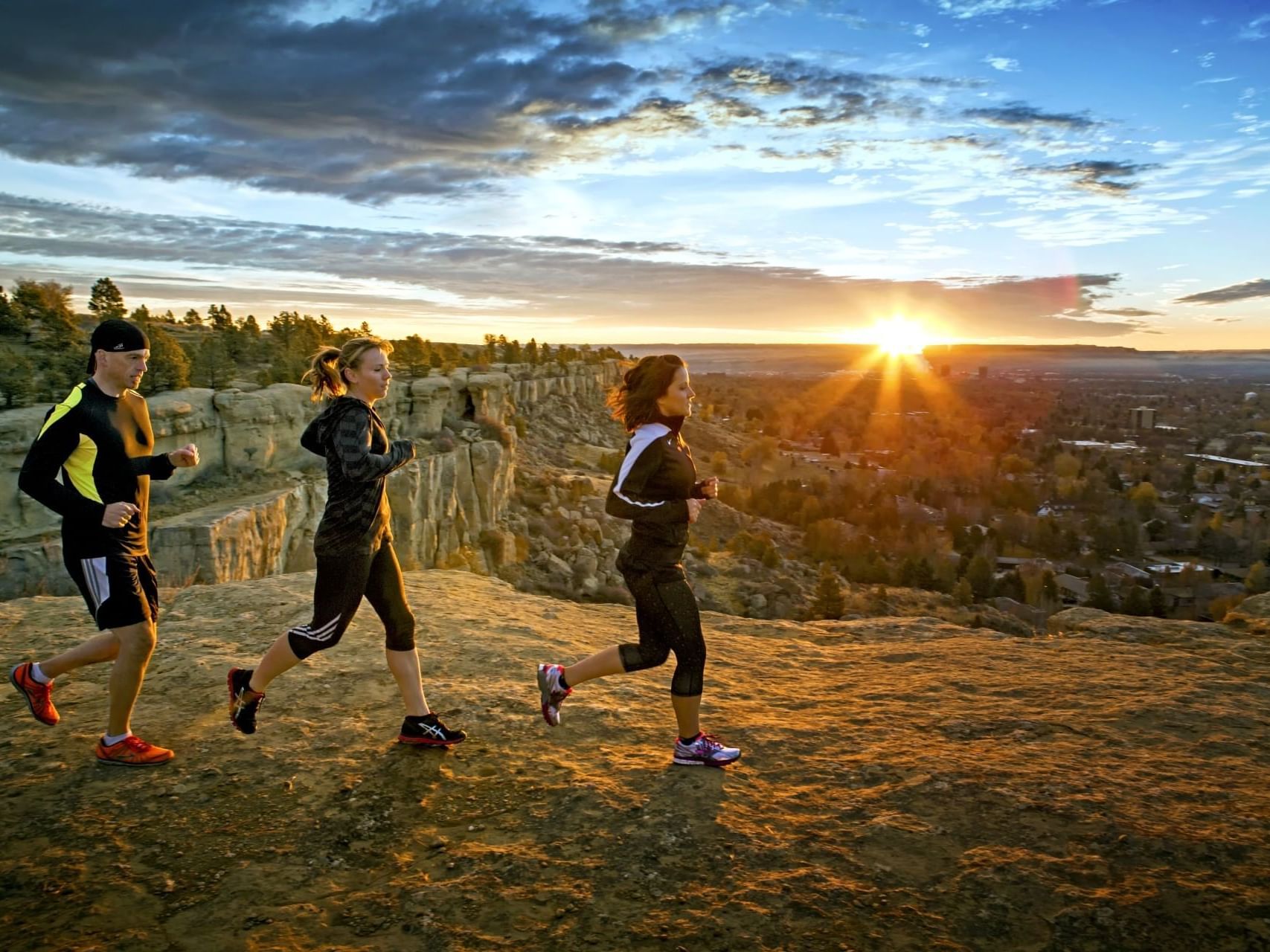 Three people jogging at Swords Rimrock Park with a mountain range view near Boothill Inn & Suites