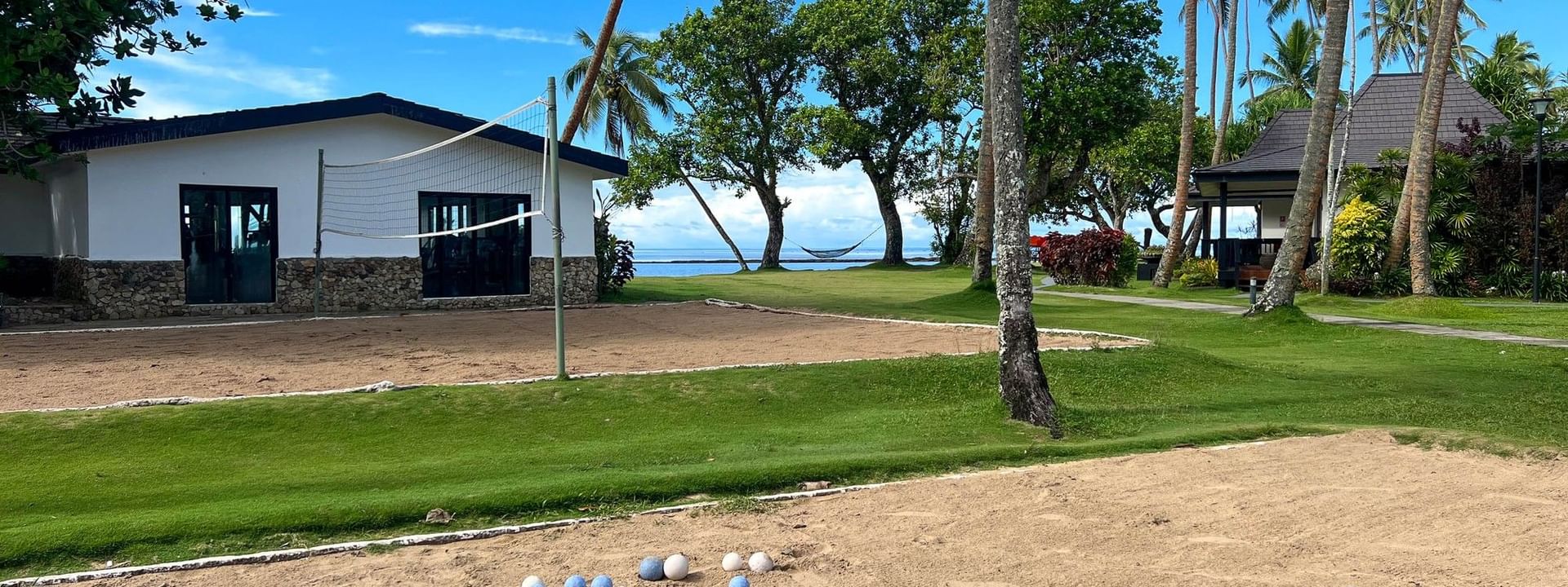 Balls arranged on sandy court with volleyball net and bungalows at The Naviti Resort in Korolevu