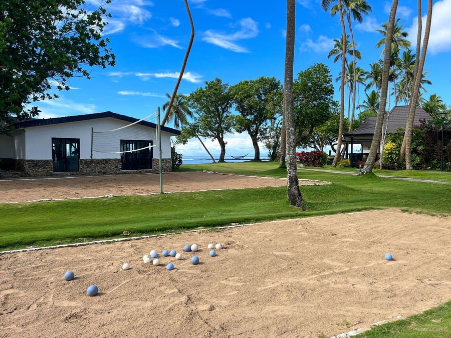 Balls arranged on sandy court with volleyball net and bungalows at The Naviti Resort in Korolevu