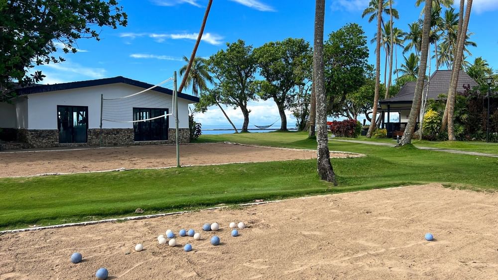 Balls arranged on sandy court with volleyball net and bungalows at The Naviti Resort in Korolevu.