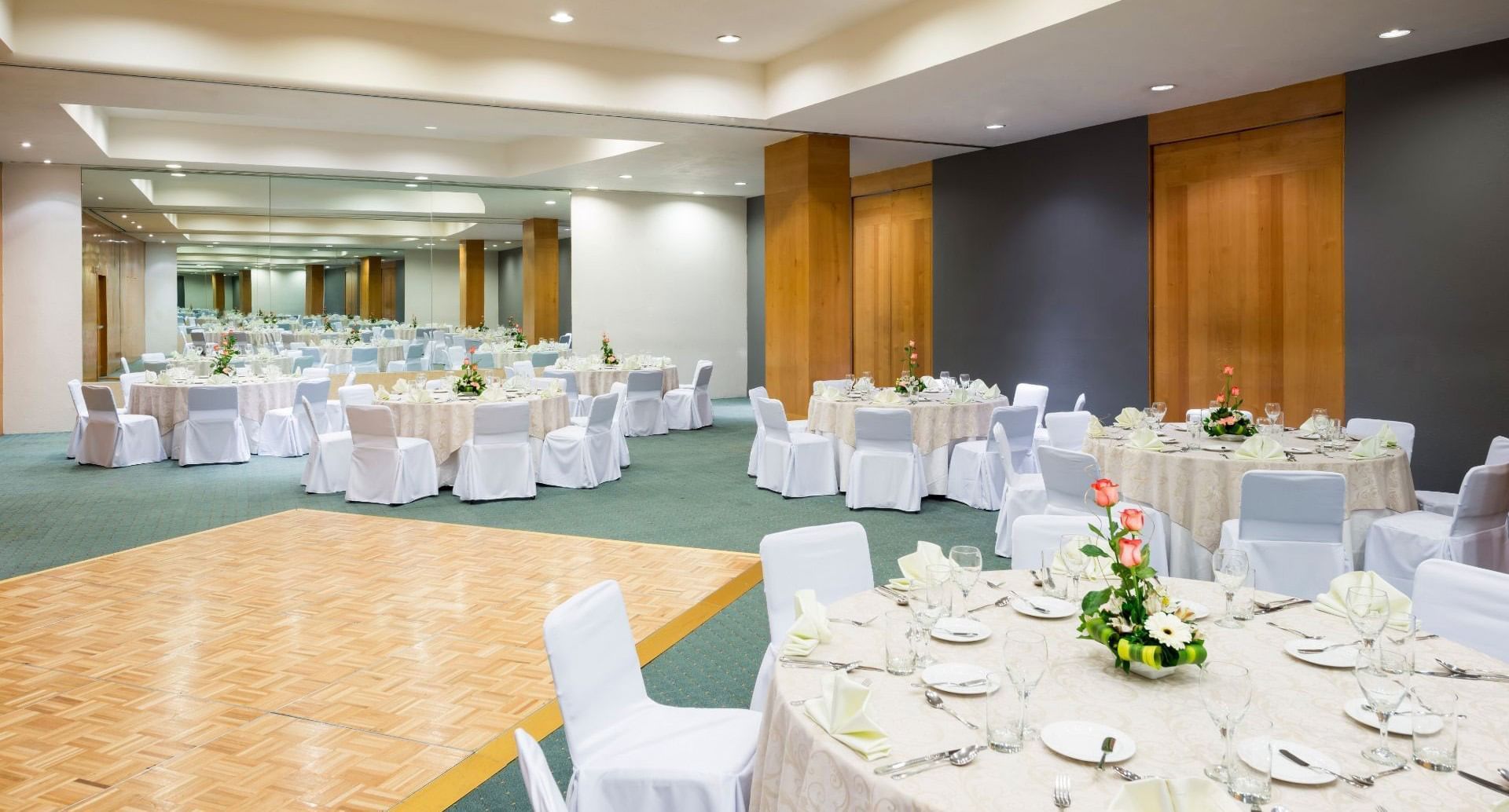 Banquetes preparados con centros florales junto a pista de baile en salón de Real Inn Perinorte