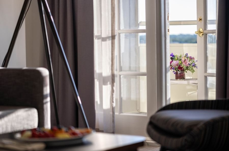 Flowers on a table by a balcony door near a tripod lamp and soft armchairs in Executive Suites at Warwick Denver