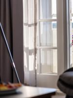 Flowers on a table by a balcony door near a tripod lamp and soft armchairs in Executive Suites at Warwick Denver
