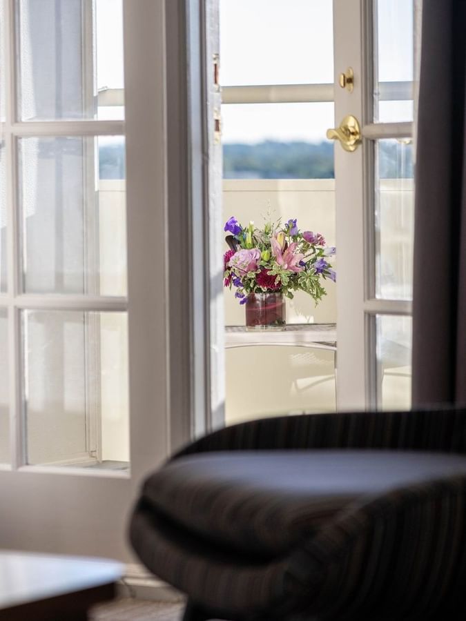 Fresh flowers on a table by a white door under bright sunlight on a balcony in Executive Suites at Warwick Denver