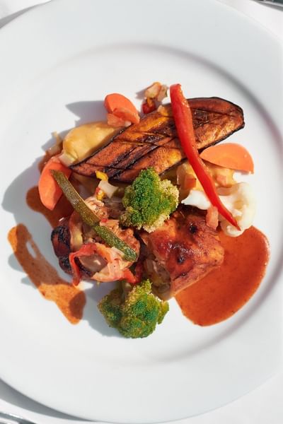 Vibrant plate of grilled chicken, plantains, and assorted vegetables served at Bay Gardens Hotel