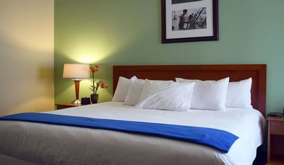 Close up on the king bed & lamp in a room at UMass Lowell Inn