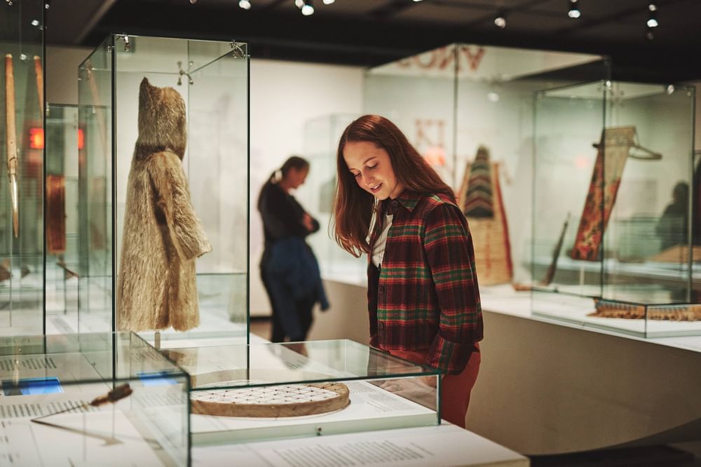 Woman viewing historical artifacts in glass display cases at museum near Warwick Le Crystal Montreal
