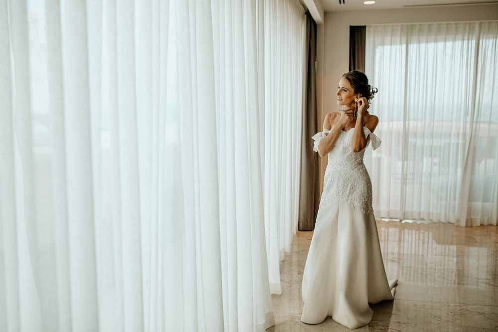 Bride posing by a tall window in a Room at Live Aqua Resorts