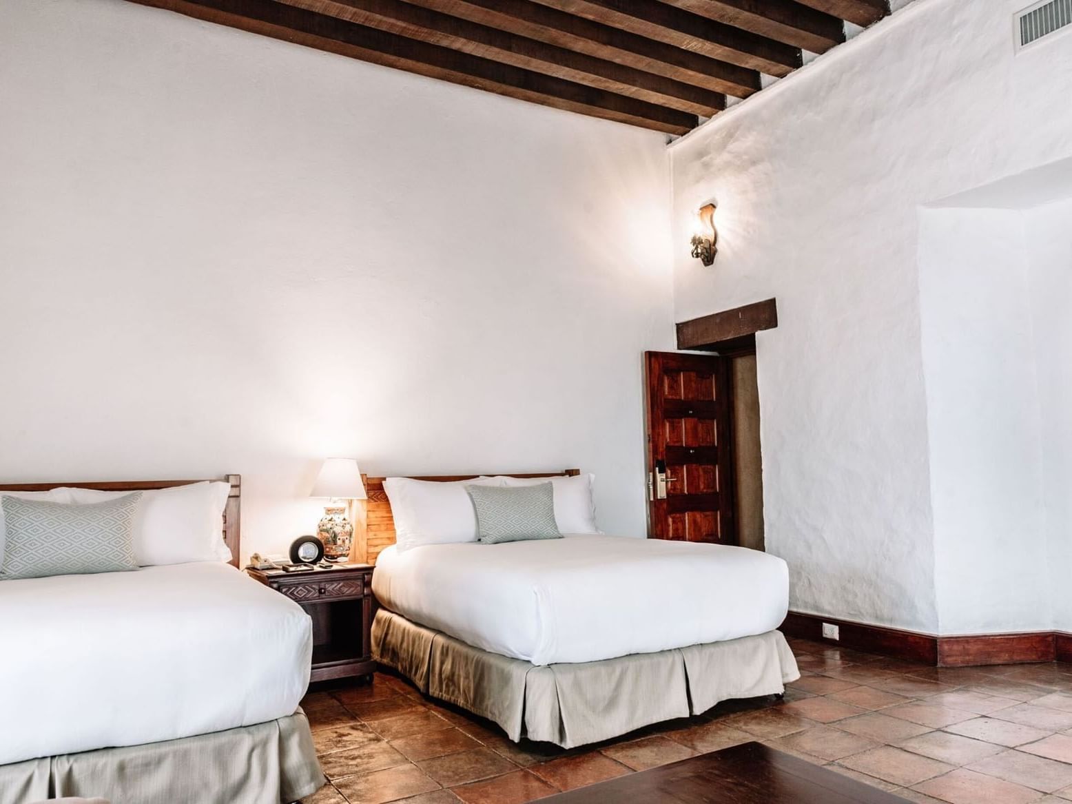 Nightstand with lamp by the cozy beds in the 2 Double Grand Class Suite at Quinta Real Oaxaca