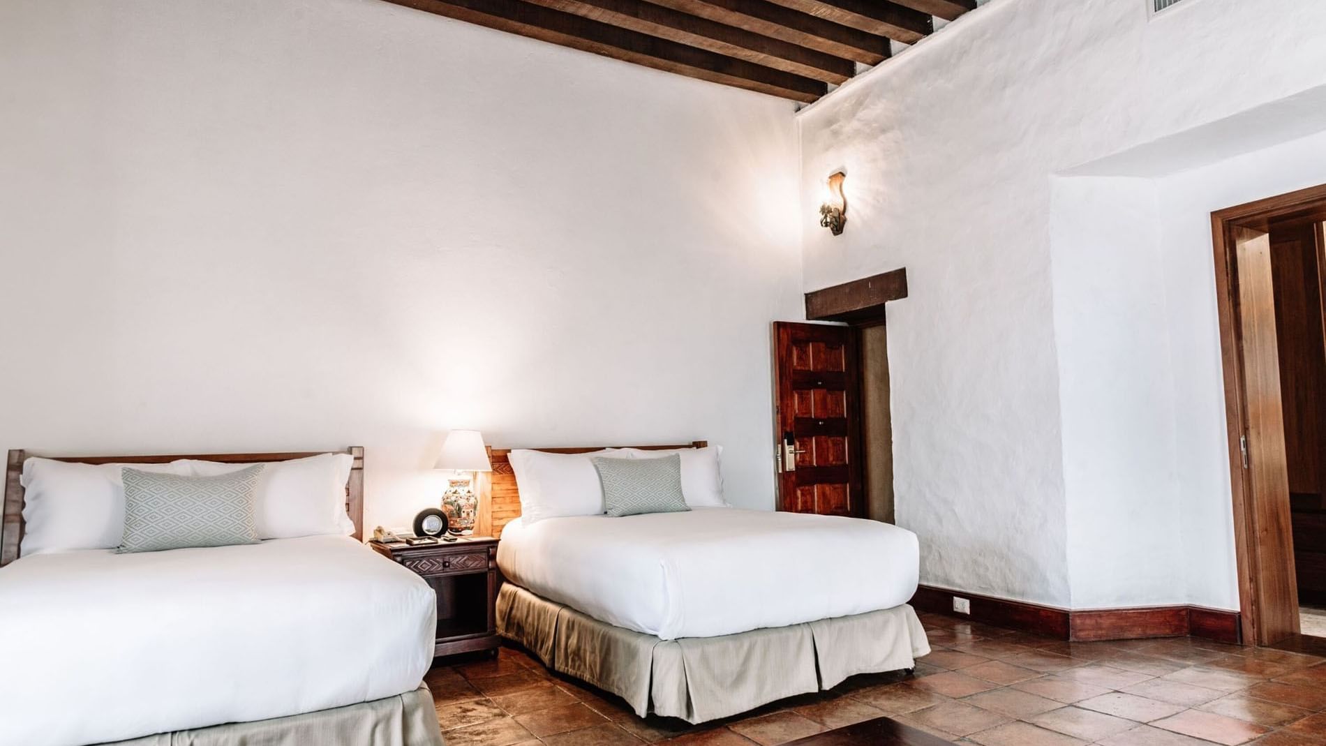 Nightstand with lamp by the cozy beds in the 2 Double Grand Class Suite at Quinta Real Oaxaca