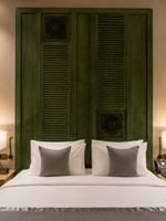 Bed beneath wood-paneled headboard between table lamps in Deluxe Skyline View at Naviti by Warwick Jeddah