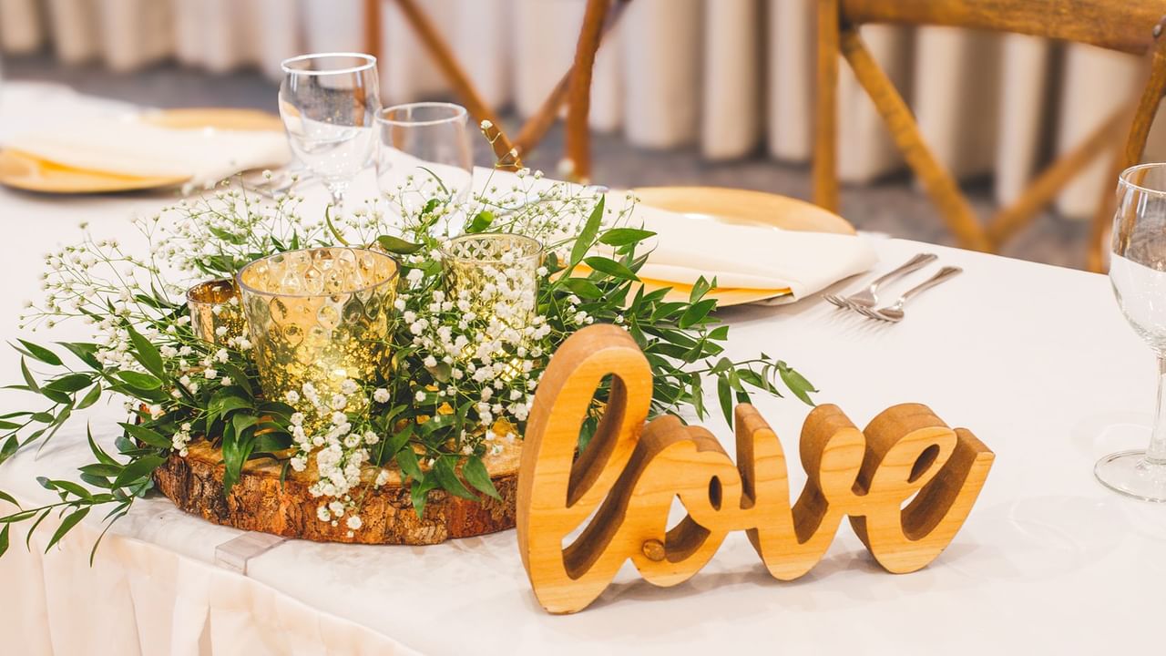 A table setting with floral arrangement, two glasses, and a wooden 