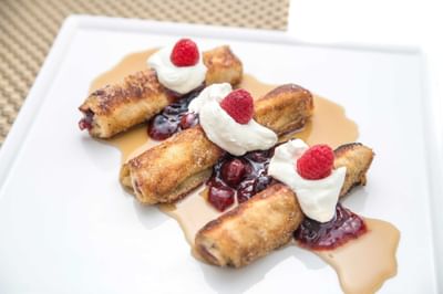 Golden French toast roll-ups over berry compote and syrup served on a white plate at The Saujana Hotel Kuala Lumpur