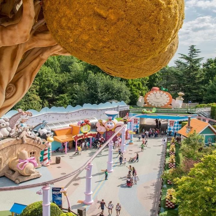 A whimsical theme park with colorful structures, pathways, and a large golden tree-like structure.