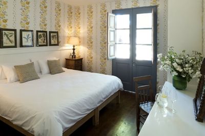 Large bed by a wooden nightstand under floral wallpaper by a blue door in a room at NOI Blend Colchagua, Chile