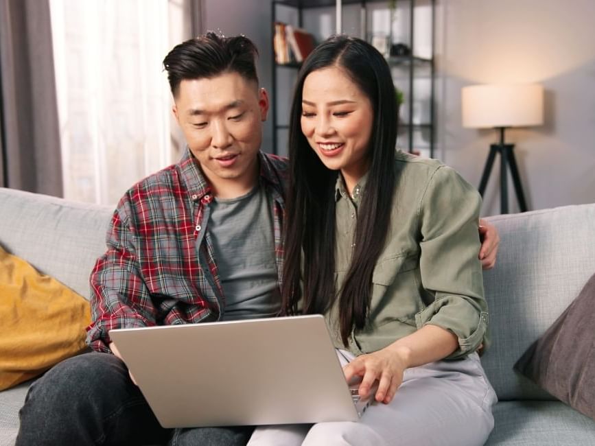 Two people sitting on a sofa using a laptop at Sandman Hotel & Suites Winnipeg Airport, Winnipeg hotels near airport