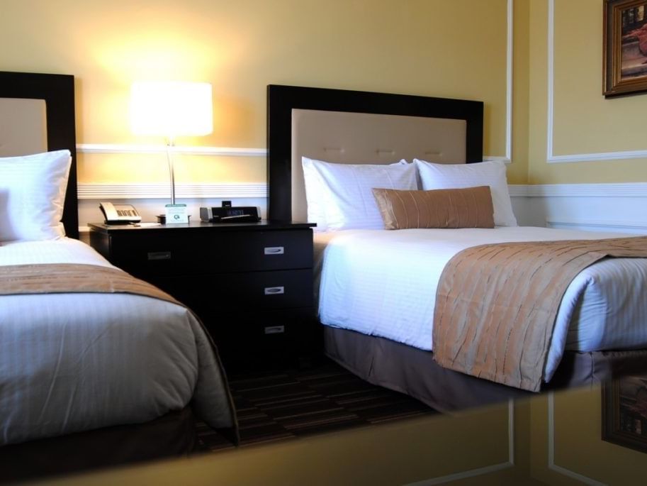 Two beds with pillows and nightstand with lamp in a hotel room at Pickwick San Francisco.